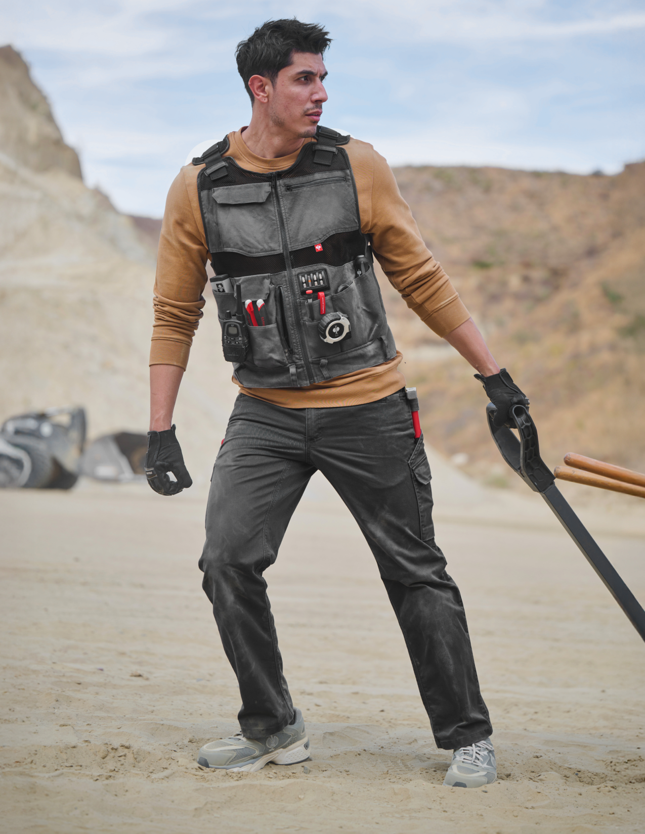 Person wearing a tactical vest with tools in a desert setting